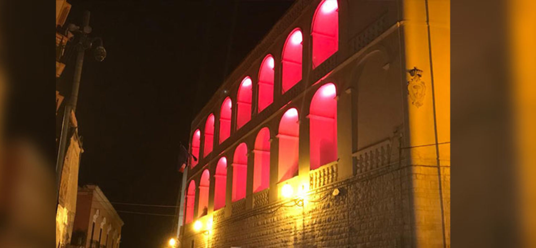 La facciata del Palazzo di Città colorata di rosso Adisco